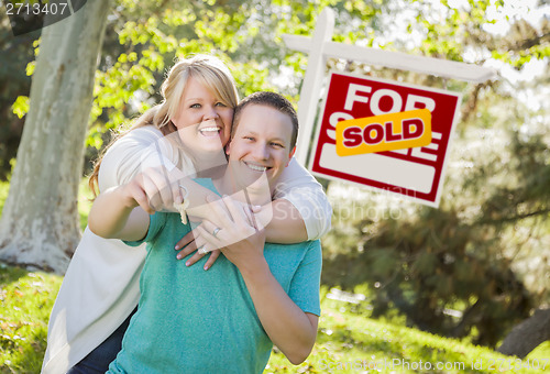 Image of Couple In Front of Sold Real Estate Sign Holding Keys