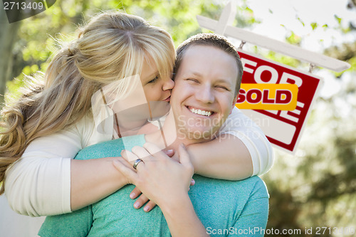 Image of Happy Couple In Front Sold Real Estate Sign