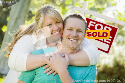 Image of Happy Couple In Front Sold Real Estate Sign