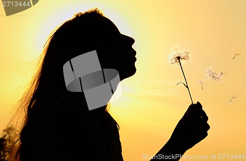 Image of silhouette of girl blowing to dandelion