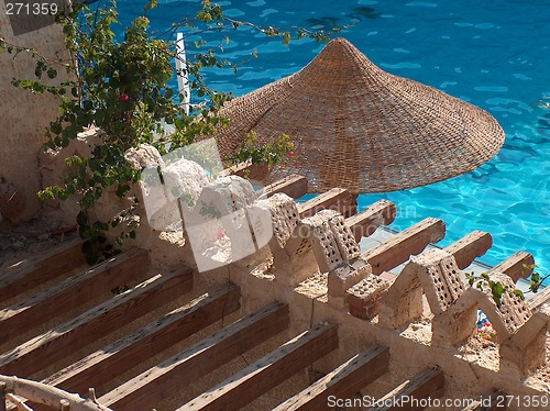 Image of Beach umbrella, straw circular, against water surface