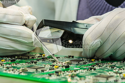 Image of Woman in antistatic gloves holding pincette and magnifier