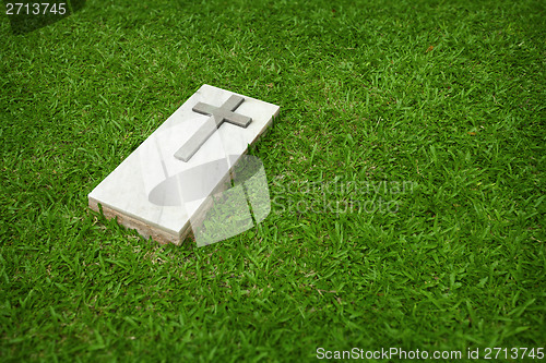 Image of Marble tombstone with the Christian cross on a green lawn