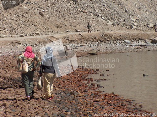 Image of Veiled arab women talking and walking on a beach