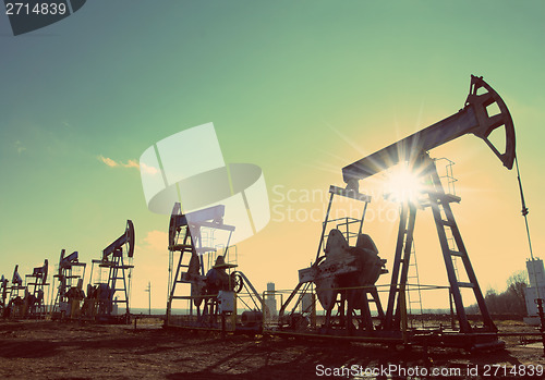 Image of oil pumps silhouette against sun - vintage retro style