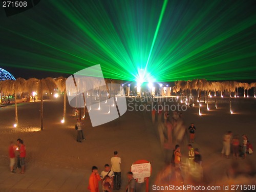 Image of The green laser at night above a beach, people among artificial