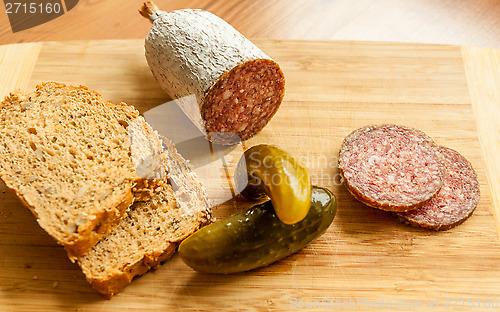 Image of Salami slices with pickles on wood background 