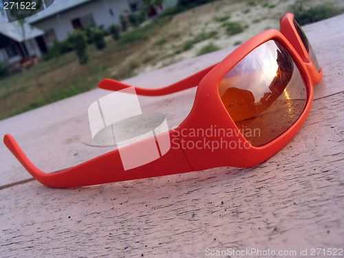 Image of bright orange sun glasses lying on the wooden table