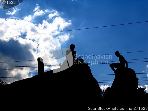 Image of shapes of two people seated on a rock in the sky