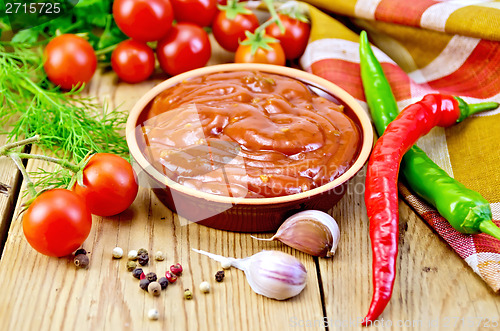 Image of Ketchup in pottery with vegetables on board