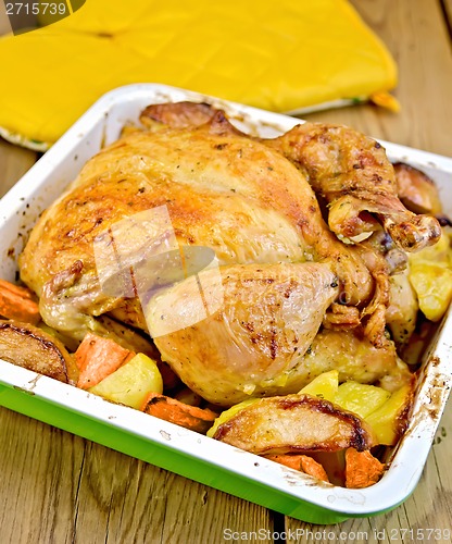 Image of Chicken baked with vegetables on board and potholders