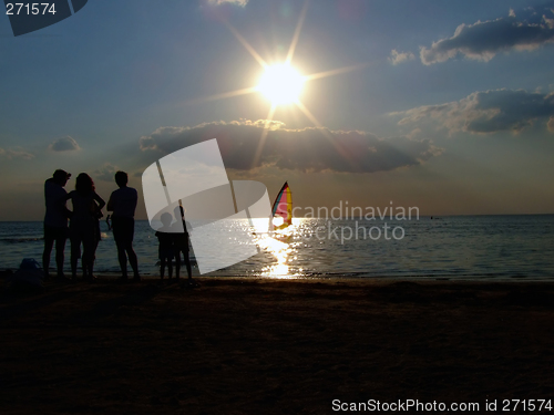 Image of Silhouette of people looking at windsurf at sunset