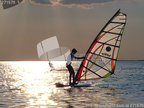 Image of A women is learning windsurfing at the sunset
