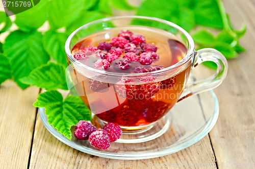Image of Tea with raspberry and green leaves on board