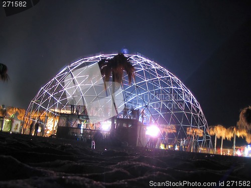 Image of people dancer with a metal dome on the beach at night