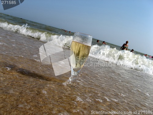 Image of Glass of a cold champagne in warm sea waves on a beach 1