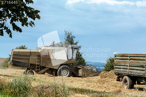 Image of old combine on field harvesting gold wheat