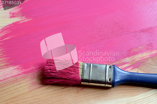Image of Paint-covered paintbrush on painted wood