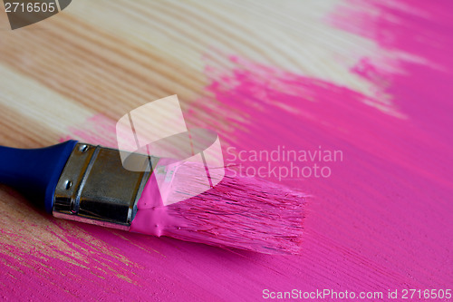 Image of Used paintbrush on half-painted pine board