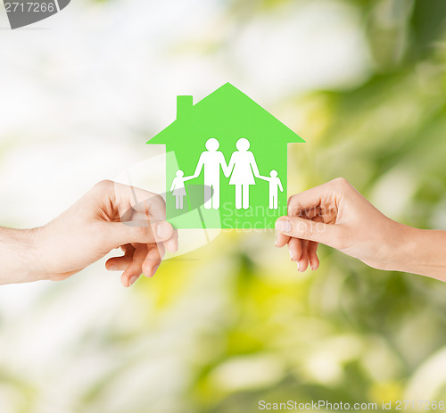 Image of hands holding green house with family