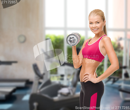 Image of smiling woman with heavy steel dumbbell