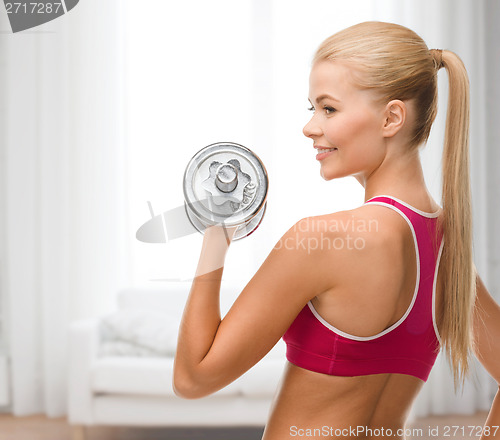 Image of smiling woman with heavy steel dumbbell