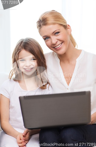 Image of smiling mother and little girl with laptop at home
