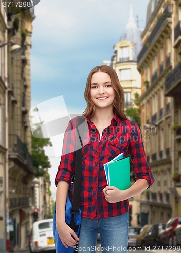 Image of smiling female student with bag and notebooks