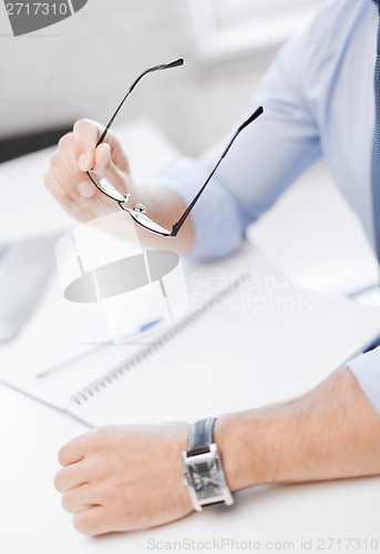 Image of businessman with spectacles writing in notebook