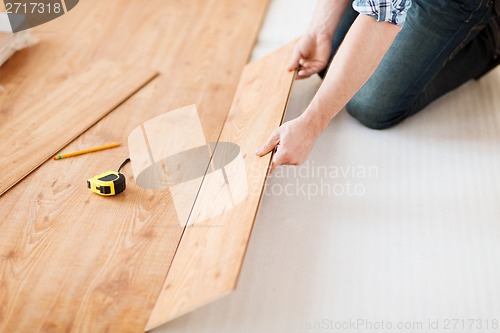 Image of close up of male hands intalling wood flooring