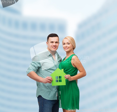 Image of smiling couple holding green paper house