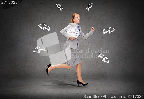 Image of stressed young businesswoman with clock running
