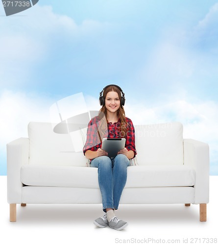 Image of girl sitting on sofa with headphones and tablet pc