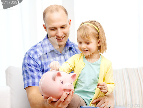 Image of happy father and daughter with big piggy bank