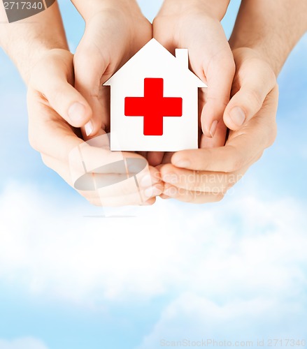 Image of hands holding paper house with red cross