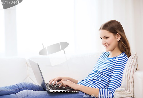 Image of smiling teenage girl with laptop computer at home