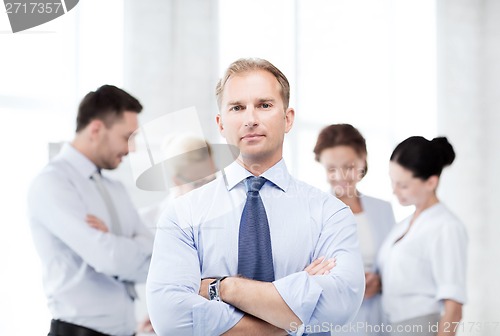 Image of handsome businessman with team in office