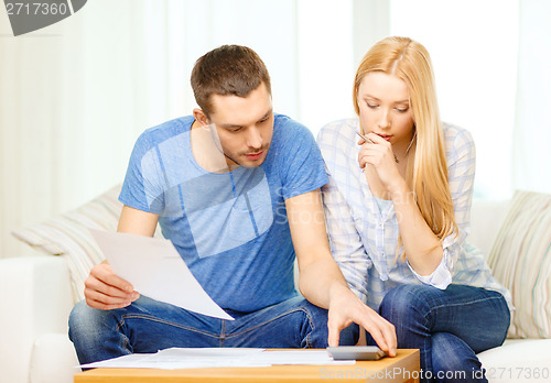 Image of busy couple with papers and calculator at home