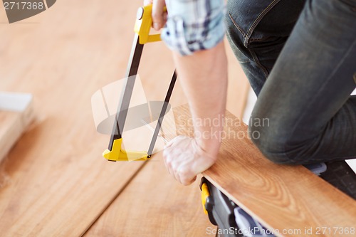 Image of close up of male hands cutting parquet floor board