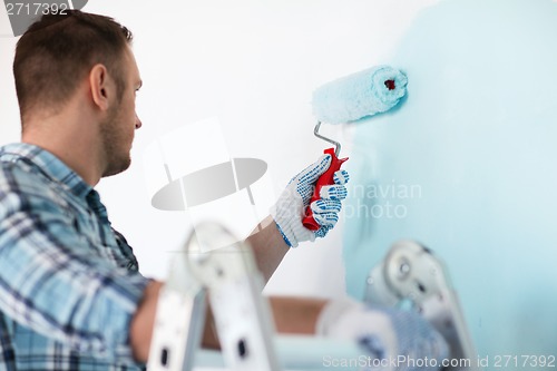 Image of close up of male in gloves holding painting roller