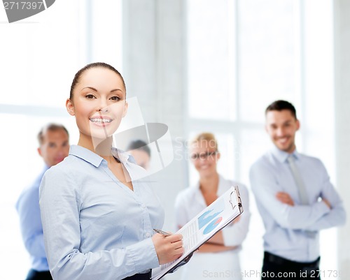Image of young smiling businesswoman with clipboard and pen