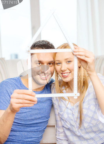 Image of smiling couple with house from measuring tape