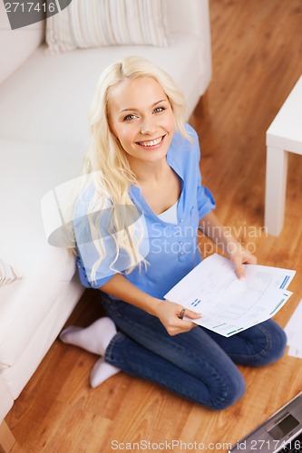 Image of smiling woman with papers, laptop and calculator