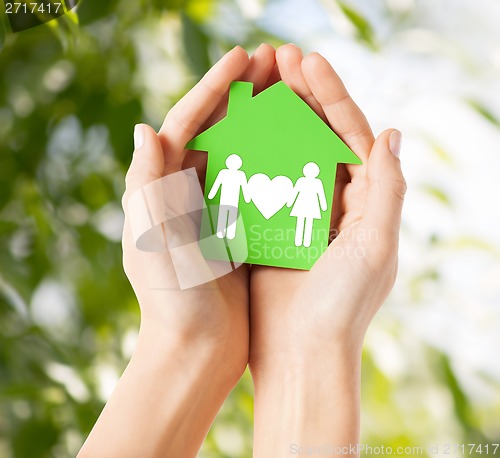 Image of hands holding green house with family