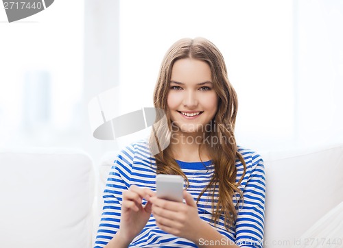 Image of smiling teenage girl with smartphone at home