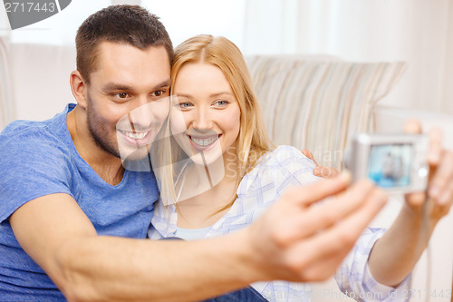 Image of smiling couple taking picture with digital camera