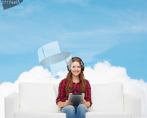 Image of girl sitting on sofa with headphones and tablet pc