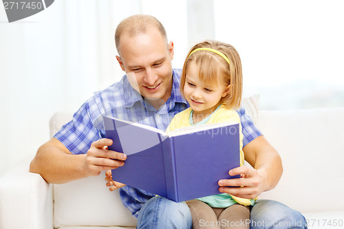 Image of smiling father and daughter with book at home