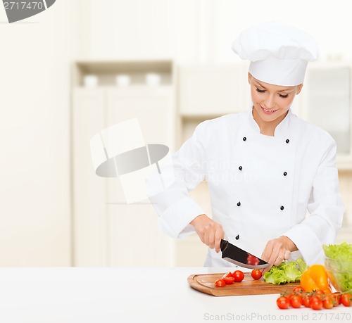 Image of smiling female chef chopping vagetables