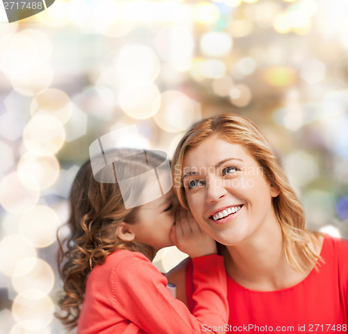 Image of smiling mother and daughter whispering gossip